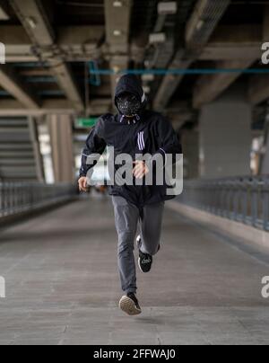 Schwarze Maske mit Nieten auf schwarzem Kapuzenpulli gekleideten Mann Stockfoto