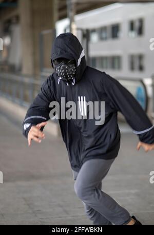 Schwarze Maske mit Nieten auf schwarzem Kapuzenpulli gekleideten Mann Stockfoto