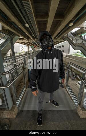 Schwarze Maske mit Nieten auf schwarzem Kapuzenpulli gekleideten Mann Stockfoto