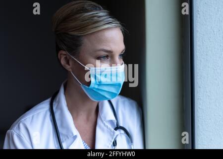 Porträt einer kaukasischen Ärztin mit Maske und Blick nach vorne Stockfoto