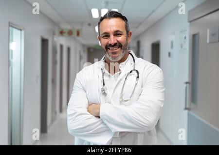 Porträt eines männlichen Arztes mit gemischter Rasse, lächelnd und stehend Krankenhausflur Stockfoto