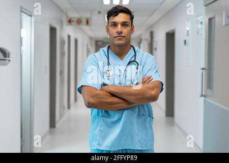Porträt eines männlichen Arztes mit gemischter Rasse, lächelnd und stehend Krankenhausflur Stockfoto