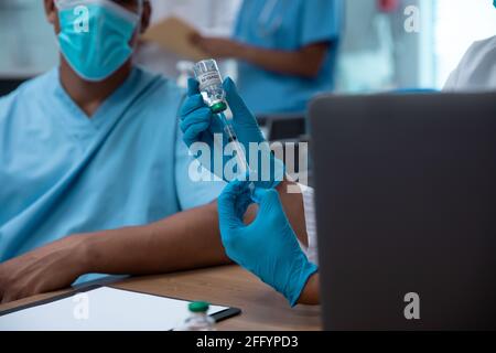 Gemischtes Rennen paar Ärzte tragen Gesichtsmasken Vorbereitung Injektion vornehmen Stockfoto