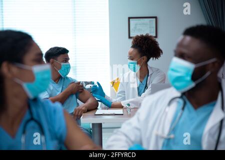 Gemischte Rasse paar Ärzte tragen Gesichtsmasken machen Injektion Stockfoto