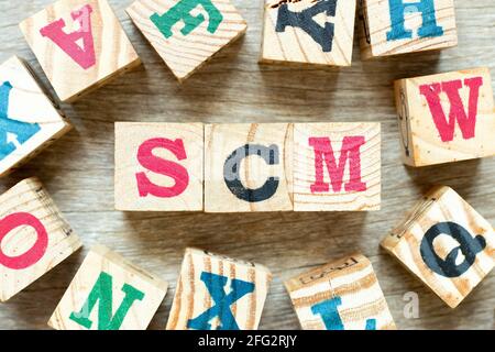 Buchstabenblock im Wort SCM (Abkürzung für Supply Chain Management) mit einem weiteren auf Holzhintergrund Stockfoto