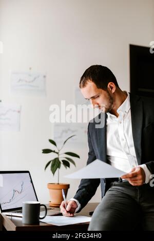 Konzentrierter junger Geschäftsmann, der im Büro am Laptop arbeitet Stockfoto