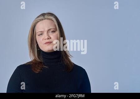 Die verrickende Frau auf dem Hintergrund in einem schwarzen Pullover Stockfoto