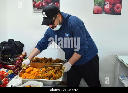 Tunis, Tunesien. April 2021. Ein tunesischer Freiwilliger bereitet sich darauf vor, während des muslimischen Fastenmonats Ramadan in der Ariana bei Tunis kostenlose Iftar-Mahlzeiten an benachteiligte Menschen zu verteilen.EIN Restaurant im Distrikt Ariana erhält Hilfe von den Bewohnern (einem der Arbeiterviertel von Tunis), Verteilt ein kostenloses Iftar-Essen an mehr als 200 arme Tunesier und afrikanische Einwanderer während des Fastenmonats der Muslime im Ramadan. Kredit: SOPA Images Limited/Alamy Live Nachrichten Stockfoto