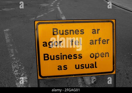 Business Open as usual Schild, in Englisch und Walisisch, Warnung vor Straßenarbeiten vor. Mit selektiver Farbgebung Stockfoto