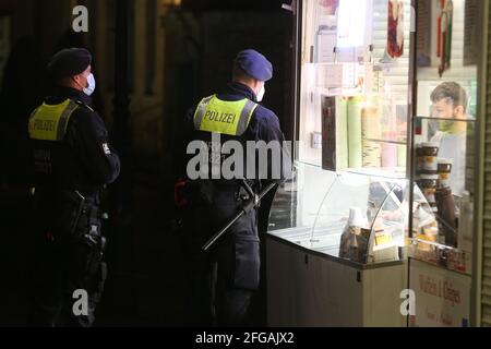 Düsseldorf, Deutschland. April 2021. Polizeibeamte aus einer Gruppe von Hunderten in der Altstadt checken kurz vor 22 Uhr ein Geschäft. Die Menschen in Deutschland müssen sich auf neue Corona-Beschränkungen vorbereiten. Kredit: David Young/dpa/Alamy Live Nachrichten Stockfoto