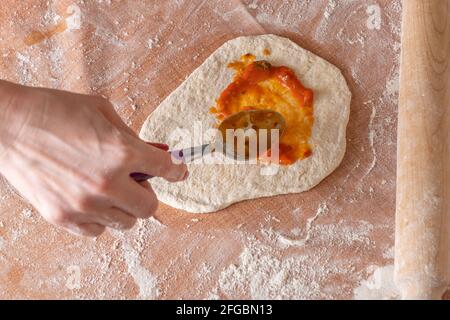 Teig durch weibliche Hände braun Tischhintergrund machen, Ansicht von oben. Stockfoto