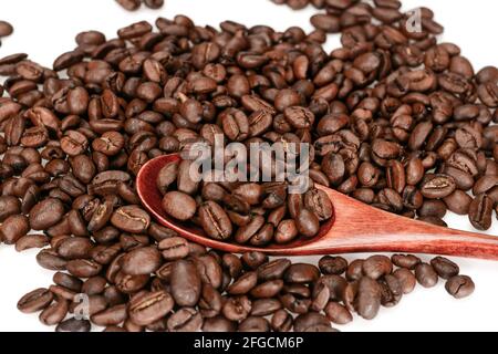 Geröstete Kaffeebohnen, dunkelbraun mit Löffel, Nahaufnahme isoliert auf weißem Hintergrund Stockfoto