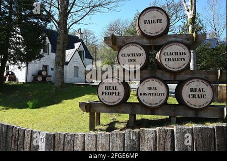 Außenansicht des berühmten Clachaig Inn in Glencoe, Schottische Highlands, sonniger Tag mit blauem Himmel. Keine Personen. Willkommen dekorative Fässer mit weiß getünchten Inn. Stockfoto