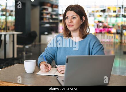 Schöne stilvolle junge Frau plus Größe Körper positiv mit Laptop im Schönheitssalon Büro, Inhaber eines kleinen Unternehmens Stockfoto