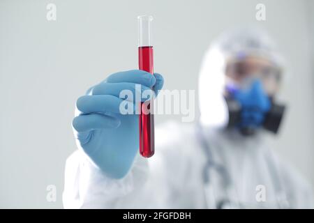 Ein Mann im Schutzanzug hält ein Reagenzglas in den Händen. Das Konzept der offenen Impfstoffe gegen Coronavirus Stockfoto