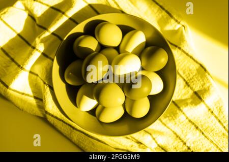 Hühnereier in einem Teller auf einem karierten Küchentuch. Konzept der landwirtschaftlichen Produkte und natürliche Ernährung. Hartes Sonnenlicht und Schatten. Getönte in Beleuchtung und Stockfoto