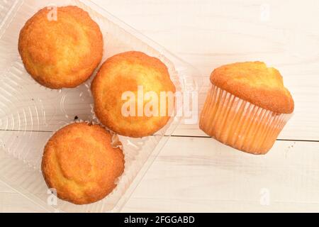 Vier duftende Cupcakes in einer Plastikbox, Nahaufnahme, auf einem Holztisch, Draufsicht. Stockfoto