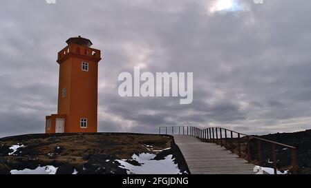 Schöne Aussicht auf den orangefarbenen Leuchtturm Svörtuloft an der rauen Nordwestküste von Snæfellsnes, Westisland in der Wintersaison mit Schnee. Stockfoto