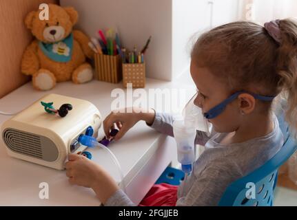 Kranke kleine Mädchen mit Inhalator am Tisch sitzen Stockfoto