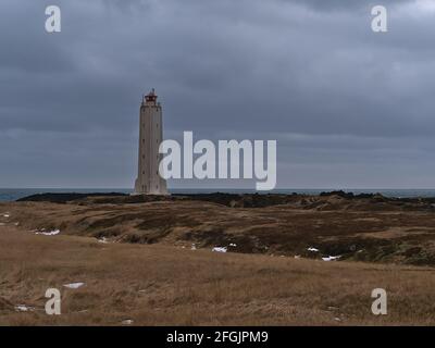 Schöner Blick auf den Leuchtturm Malarrif (Baujahr 1946) an der Westküste der Halbinsel Snæfellsnes, Westisland an bewölktem Wintertag mit braunem Gras. Stockfoto