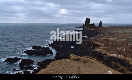 Atemberaubende Aussicht auf die Südwestküste der Halbinsel Snæfellsnes, Island mit schroffen Klippen und der berühmten vulkanischen Felsformation Lóndrangar im Winter. Stockfoto