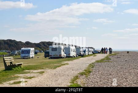 Worthing, Großbritannien. April 2021. Wanderer kommen am Campingplatz für illegale Reisende vorbei, der in Goring Gap, einem bekannten Schönheitsort am Strand in der Nähe von Worthing in West Sussex, eingerichtet wurde. In den letzten Tagen sind etwa 30 Wohnwagen und Mobilheime für Reisende angekommen, aber der Bezirksrat von West Sussex hat am 28. April eine gerichtliche Anordnung beantragt, um sie zu entfernen : Quelle: Simon Dack/Alamy Live News Stockfoto