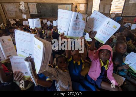 Mzuzu, Malawi. 30-05-2018. Afroabhängige Kinder, die die Schule besuchen, zeigen ihrem Lehrer stolz, dass die Hausaufgaben gemacht sind. Stockfoto