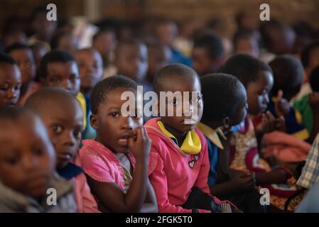 Mzuzu, Malawi. 30-05-2018. Porträt von afroabhängigen Kindern, die die Kamera in die Schule schauen, während der Lehrer in einem ländlichen Raum Unterricht gibt Stockfoto