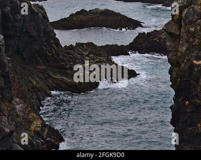 Blick auf steile Klippen aus vulkanischem Basaltgestein an der rauen südwestlichen Atlantikküste der Halbinsel Snæfellsnes, westlich von Island in der Nähe von Arnarstapi. Stockfoto