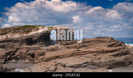 Blick auf Playa de las Catedrales in Ribadeo, Galicien, mit dem Meer im Hintergrund und bewölktem Himmel. Stockfoto