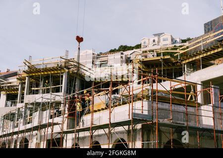 Bauarbeiter bauen ein modernes Hochhaus. Der Kran arbeitet Stockfoto