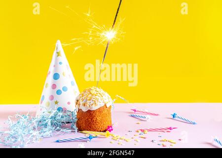 Festlicher Cupcake mit Glitzer auf gelbem Hintergrund. Dekorationen für einen Geburtstag oder Urlaub. Stockfoto