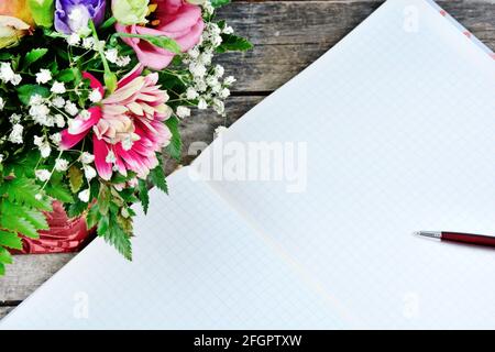 Leeres Notizbuch mit Stift und Blumen auf einem alten Holztisch. Draufsicht Stockfoto