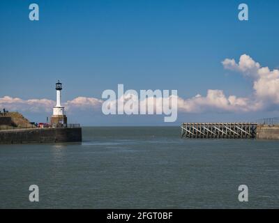 Der Eingang zum Maryport Harbour an der Solway Coast im Nordwesten von Cumbria, England, Großbritannien. Auf der linken Seite befindet sich der älteste Leuchtturm aus Gusseisen in Großbritannien, der Stockfoto