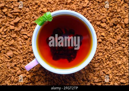 Chaga-Pilztee. Eine Tasse gebrühter Tee aus Birkenpilz-Chaga auf einem Haufen kleiner Bruchstücke Stockfoto