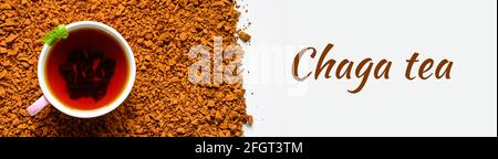 Chaga-Pilztee. Eine Tasse gebrühter Tee aus Birkenpilz-Chaga auf einem Haufen kleiner gebrochener Stücke isoliert auf weißem Hintergrund. Banner. Text der Schriftart Stockfoto