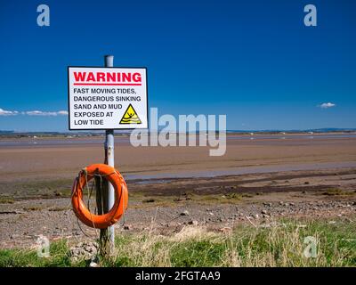 An der nordwestlichen Cumbria Solway Coast warnt ein Schild vor gefährlichen Gezeiten, sinkenden Sand- und Schlammabsenkungen bei Ebbe. Stockfoto