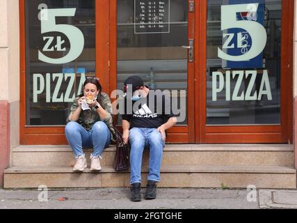 Krakau. Krakau. Polen. Ein paar junge Leute, die auf den Stufen der Pizzeria einen Snack machen mussten, waren wegen Einschränkungen geschlossen. Stockfoto