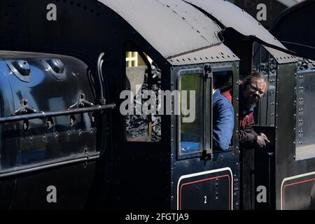 Ein Dampfzug-Fahrer lehnt sich während ihres ersten Dampfgala-Wochenendes an der East Somerset Railway von der Fußplatte am Bahnhof Cranmore, Somerset, ab, da die Sperre nachlässt. Bilddatum: Sonntag, 25. April 2021. Stockfoto