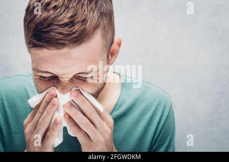 Der junge Kerl bläst in eine Papierserviette. Krankheitsbild. Erkältungen und Grippe würzen. Stockfoto