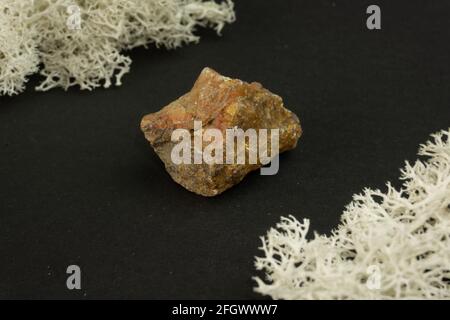 Andalusit aus Brasilien oder China. Natürlicher Mineralstein auf schwarzem Hintergrund, umgeben von Moos. Mineralogie, Geologie, Magie, Halbedelsteine und Stockfoto