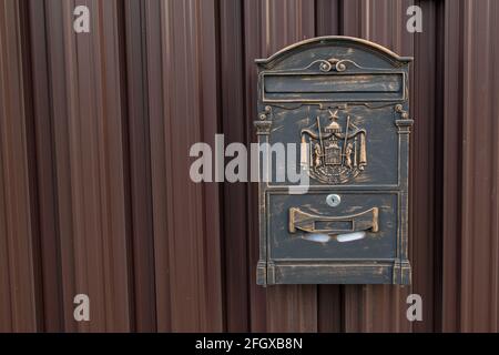 Ein schwarzer Briefkasten aus Metall für die Korrespondenz mit einem halbkreisförmigen Rand Visier an der Oberseite mit einer Gravur und Klebeband darauf, innen ist ein Umschlag befestigt t Stockfoto