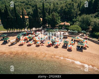 Luftaufnahme von hellen Sonnenschirmen am königlichen Strand In Przno vor dem Hintergrund von grünen Bäumen Stockfoto