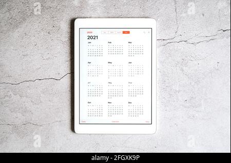 Ein Tablet mit offenem Kalender für 2021 Jahre Ein grauer Betonhintergrund Stockfoto