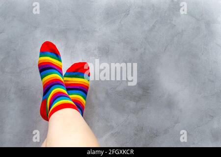 Auf grauem Hintergrund, Nahaufnahme der Füße eines Mannes in bunten Socken. Regenbogen. Symbol. Konzept-LGBT Stockfoto