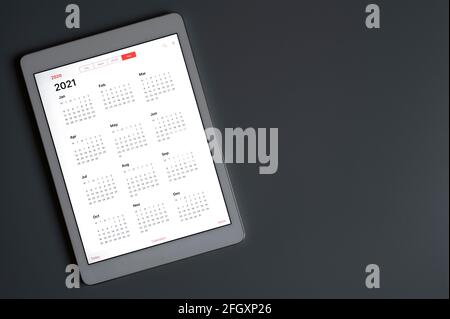 Eine Tablette mit einem offenen Kalender für 2021 Jahre auf einem dunkelgrauen hintergrundeine Tablette mit einem offenen Kalender für 2021 Jahre auf einem dunkelgrauen Hintergrund. Raum fo Stockfoto