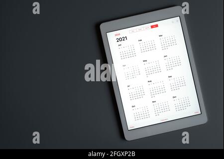 Eine Tablette mit einem offenen Kalender für 2021 Jahre auf einem dunkelgrauen hintergrundeine Tablette mit einem offenen Kalender für 2021 Jahre auf einem dunkelgrauen Hintergrund. Raum fo Stockfoto