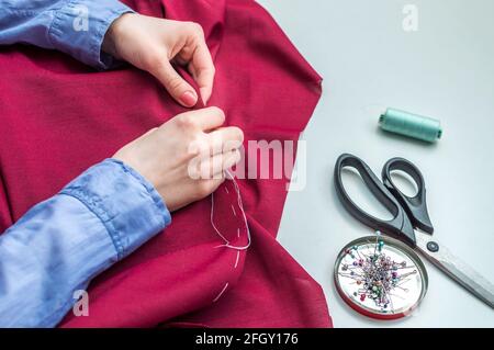 Näherin näht Kleidung von Hand. Zubehör zum Nähen. Hände von Frauen Stockfoto