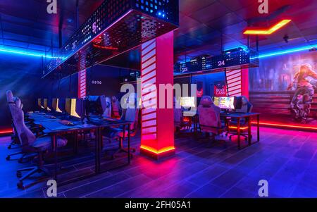 Torrevieja, Spanien - 15. April 2021: Im Inneren des leeren Internetcafés, leuchtendes, neon beleuchtetes Cybercafe-Zimmer mit Computern auf Tischen, keine Menschen. Stockfoto