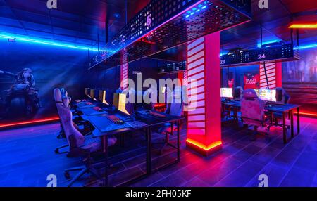 Torrevieja, Spanien - 15. April 2021: Im Inneren des leeren Internetcafés, leuchtendes, neon beleuchtetes Cybercafe-Zimmer mit Computern auf Tischen, keine Menschen. Moderne pl Stockfoto
